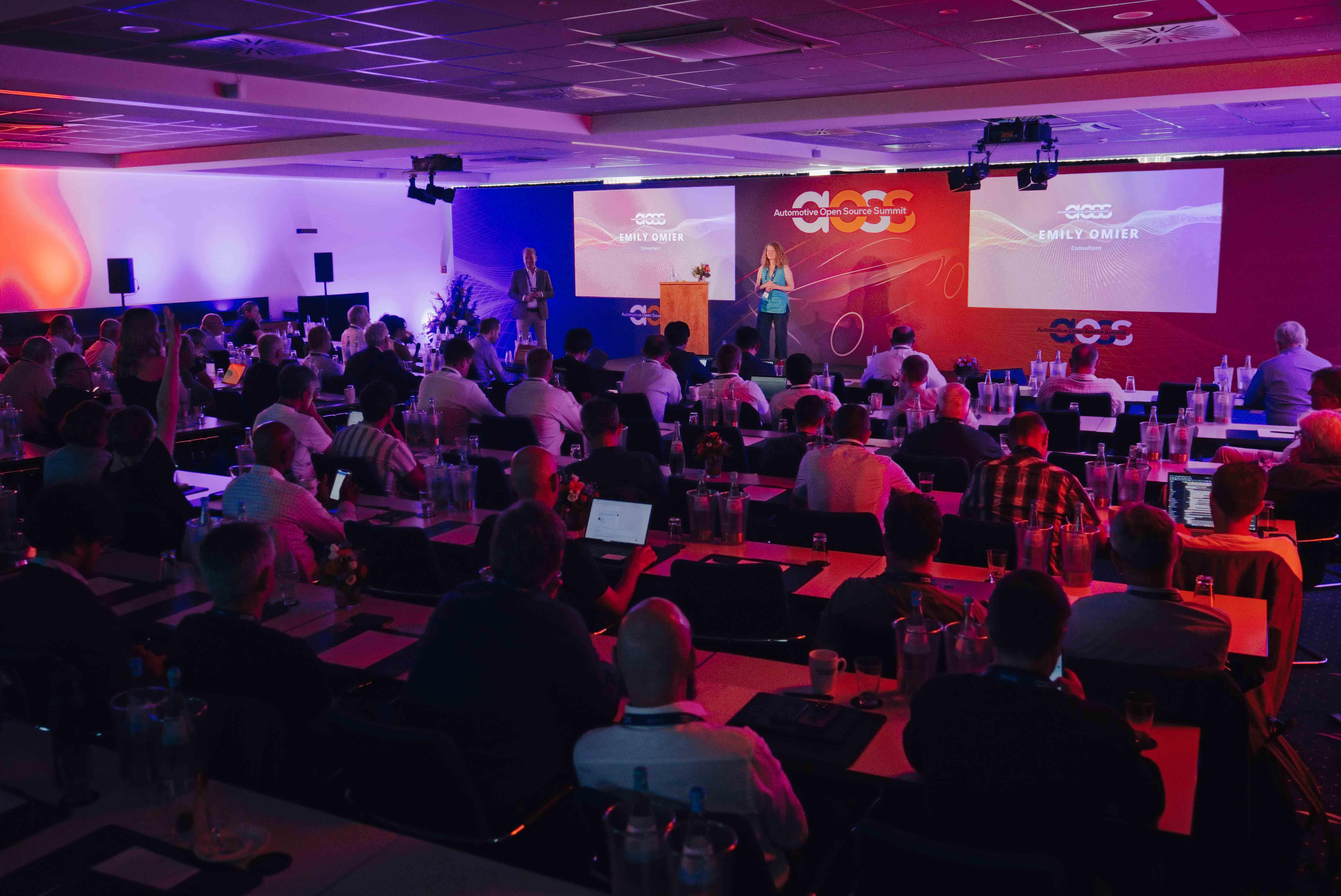 Twee sprekers zij aan zij op het podium tijdens de Automotive Open Source Summit in Starnberg