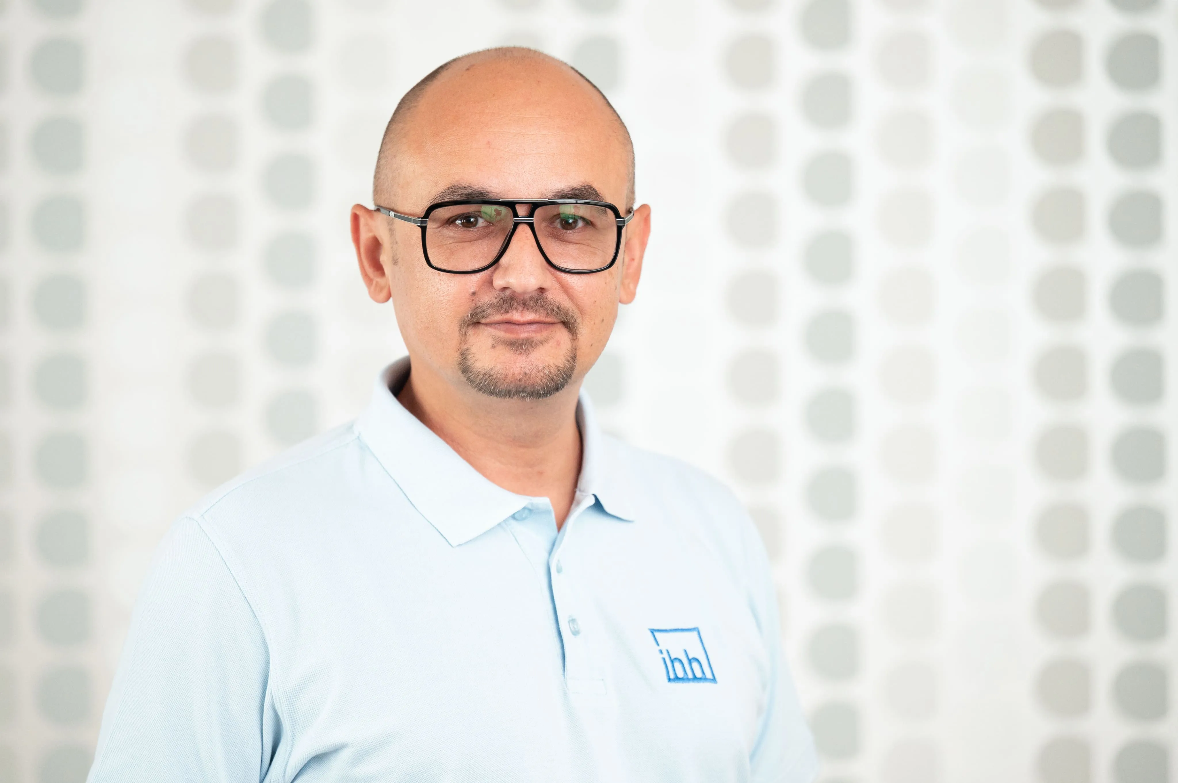 Mitarbeiterporträt eines Mitarbeiters mit Brille von Ingenieurbüro Bittner vor gemustertem Hintergrund