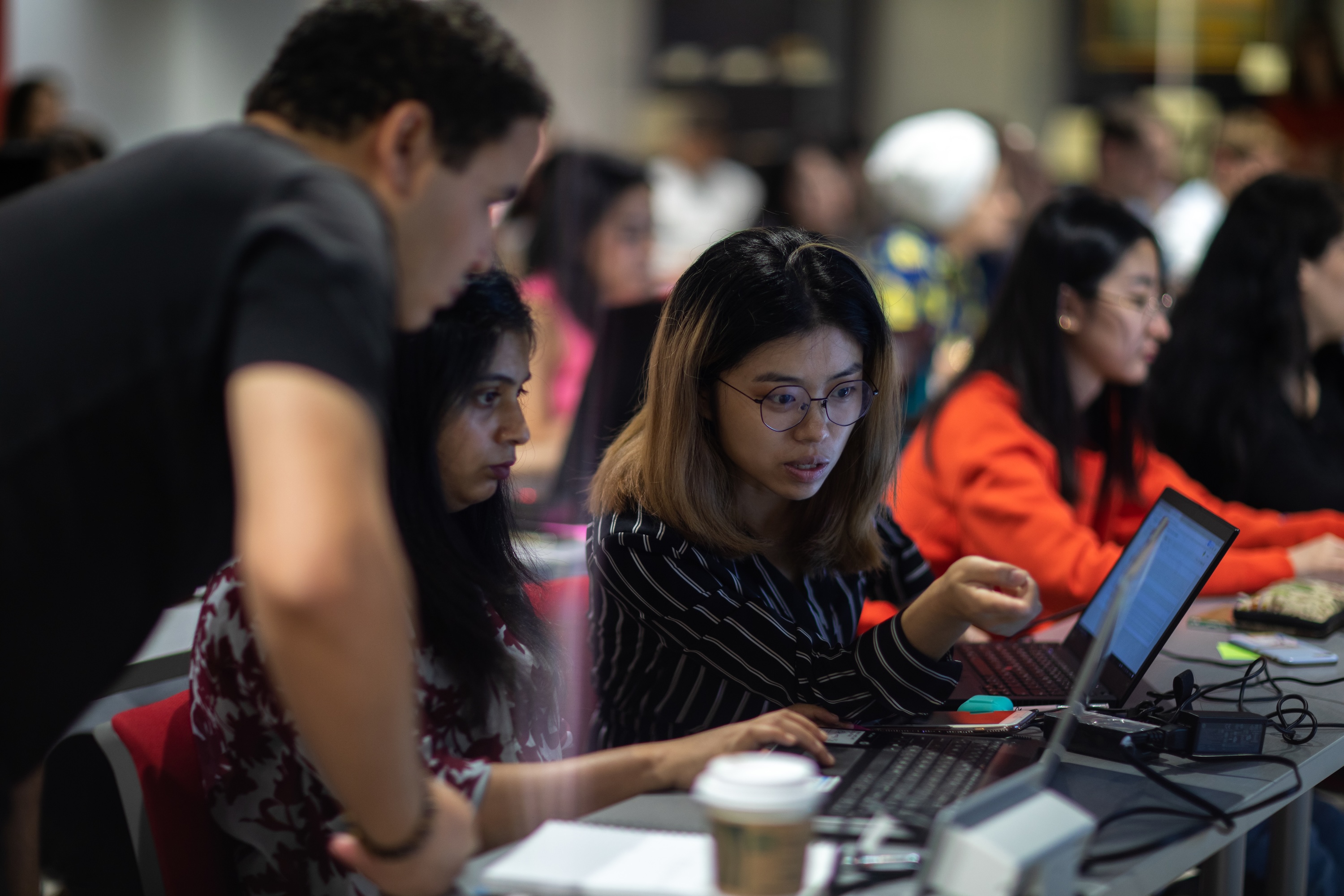 One male and two female students collaborating on a laptop during a classroom or workshop session.