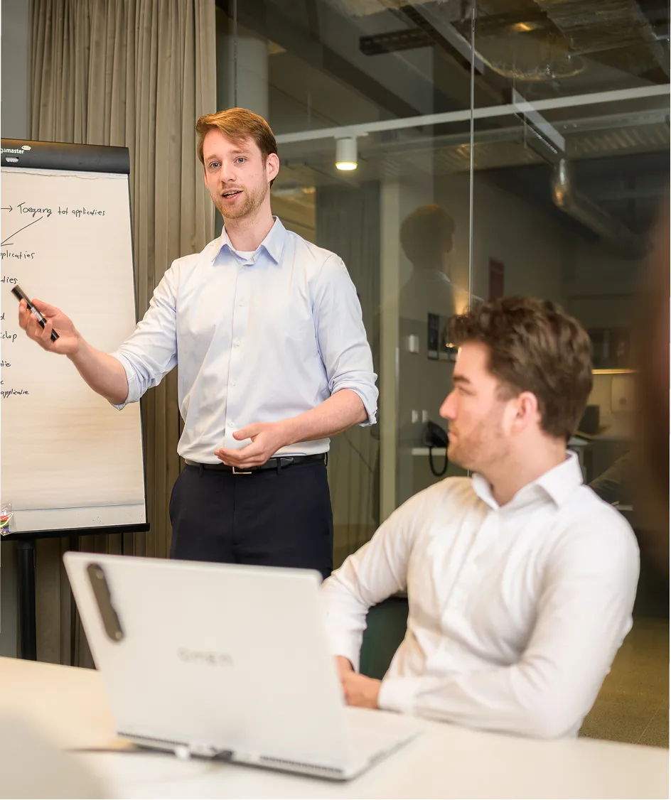 Arxion-consultant licht bij een flip-over aantekeningen toe aan een collega tijdens een werksessie