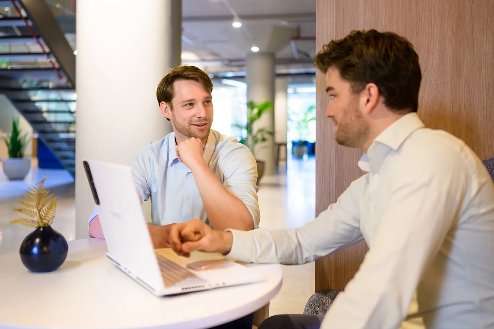 Twee Arxion-consultants overleggen aan een tafel met laptop