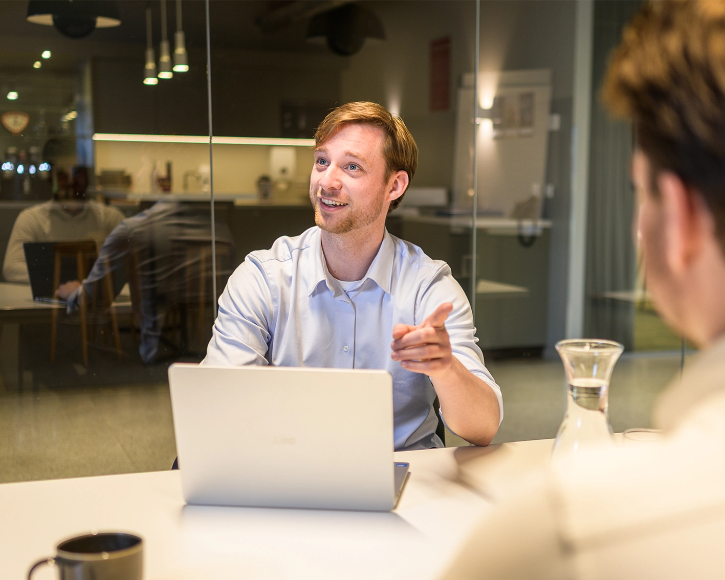 Arxion-consultant achter zijn laptop gebaart enthousiast tijdens een overleg aan tafel