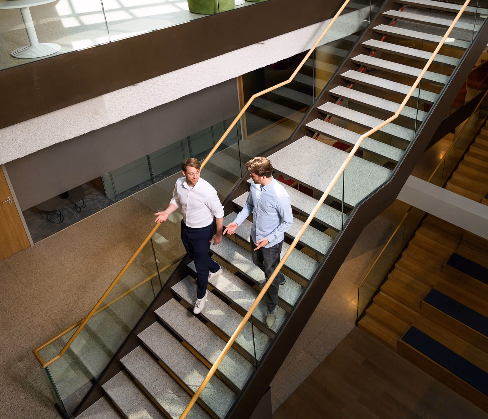 Arxion-consultants in gesprek in het kantoor in Arnhem terwijl ze van een trap aflopen