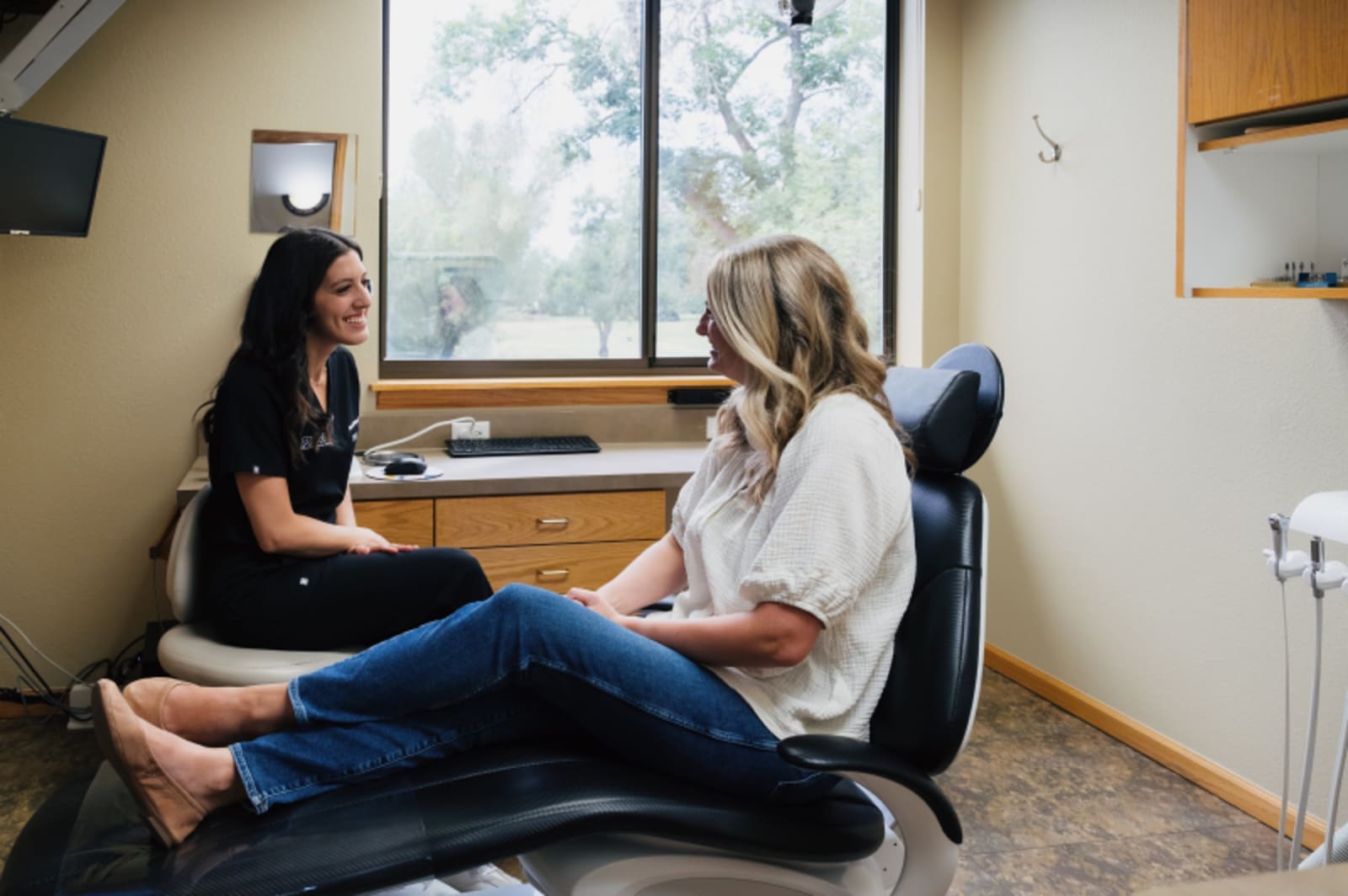 Female dentist consulting with patient in dental chair showing confidence and care