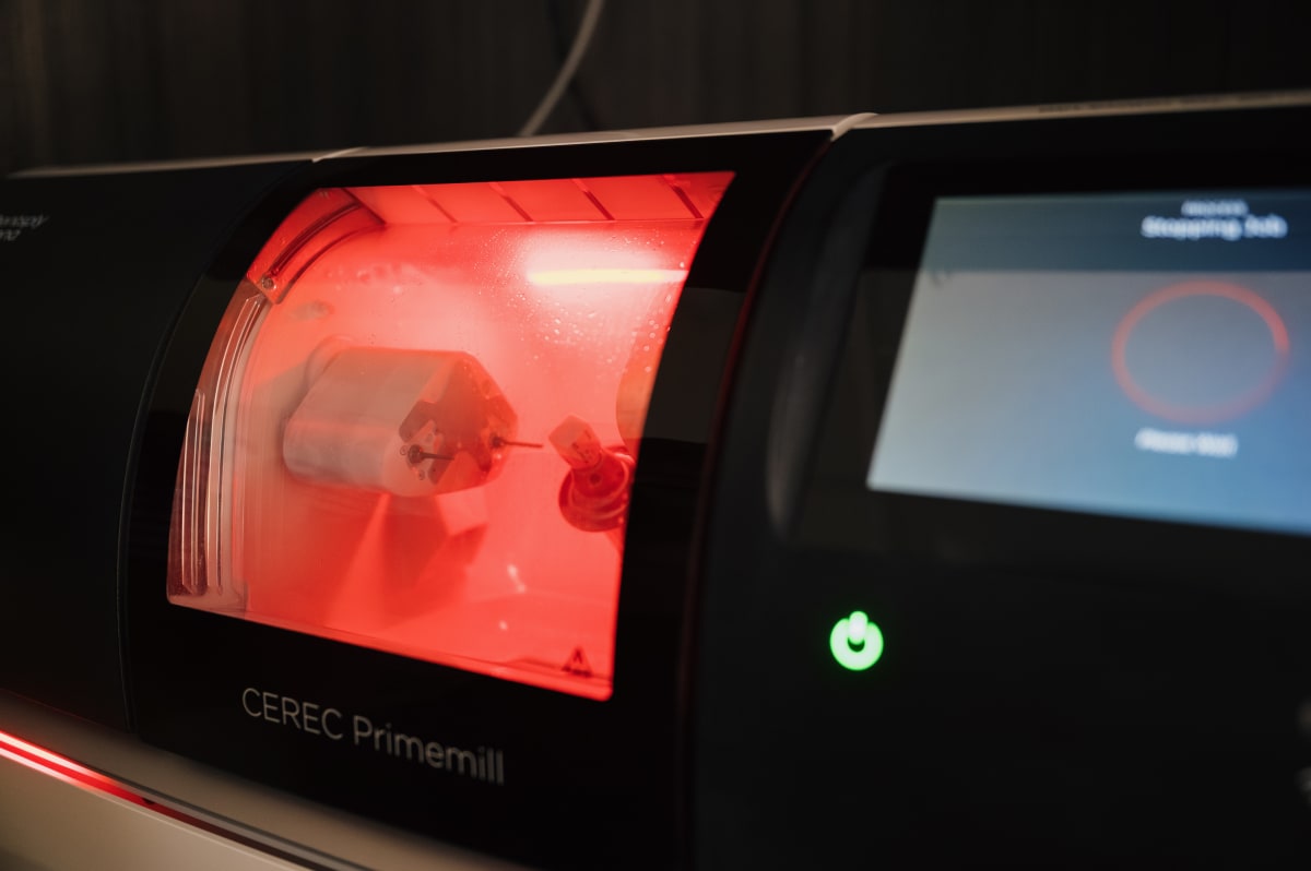 Close-up of a dental milling machine with red light and digital display screen.