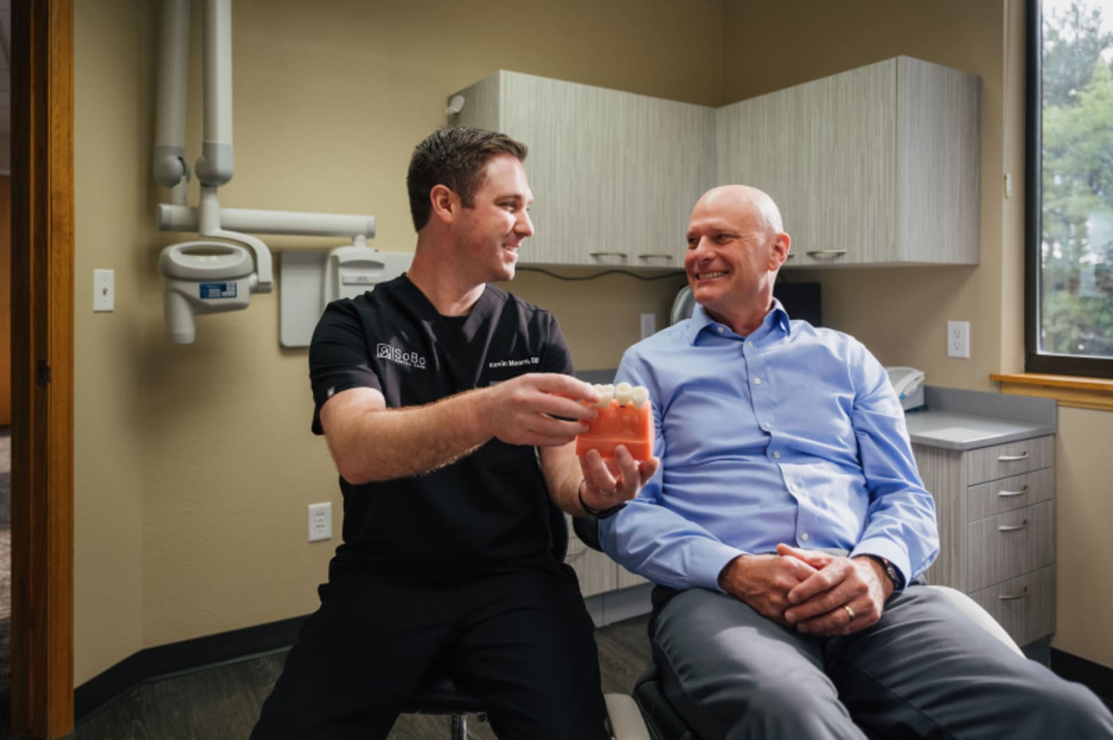 Dentist showing digital 3D crown design on monitor to seated patient