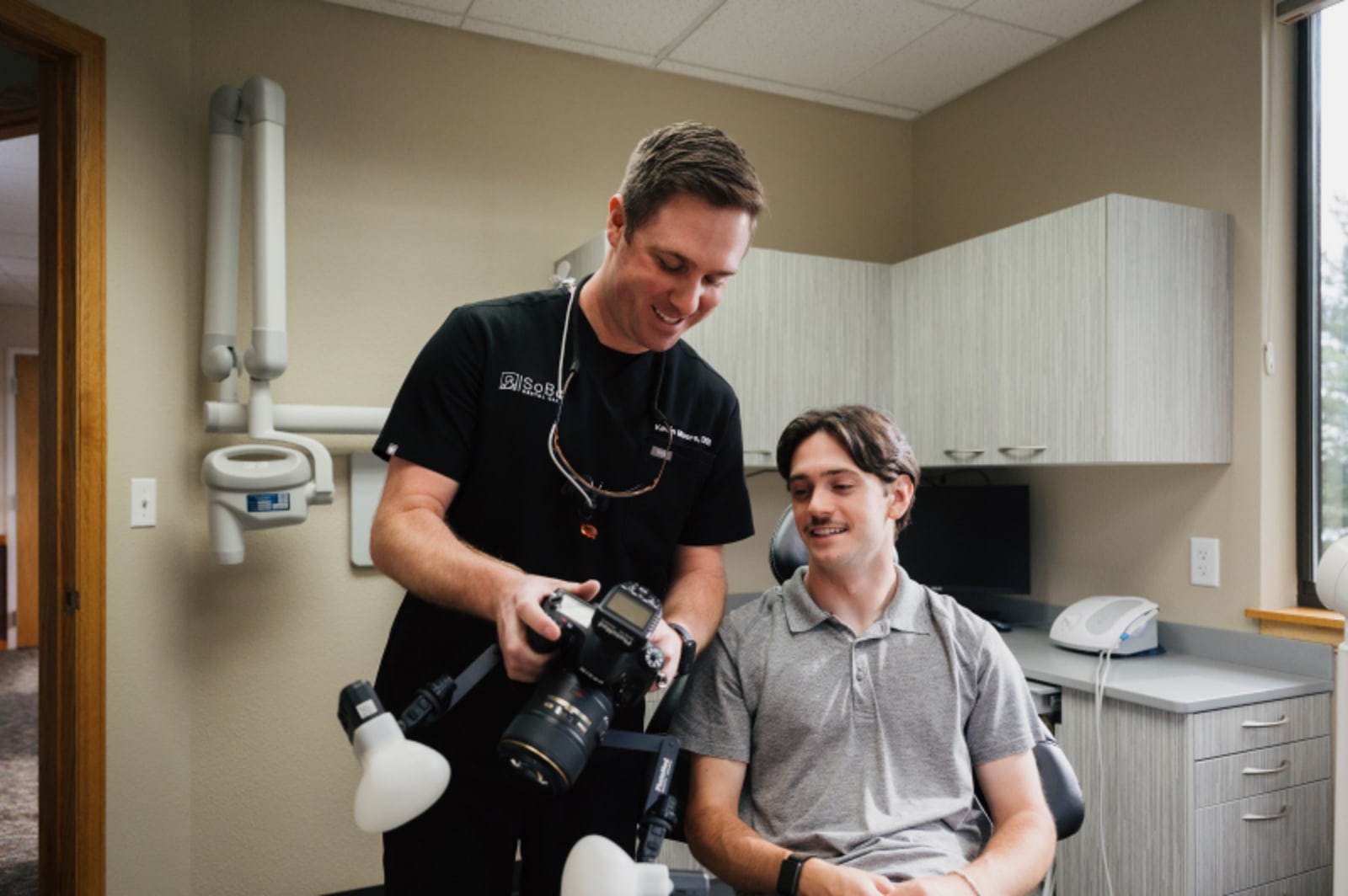 Dentist explaining treatment to patient in examination chair