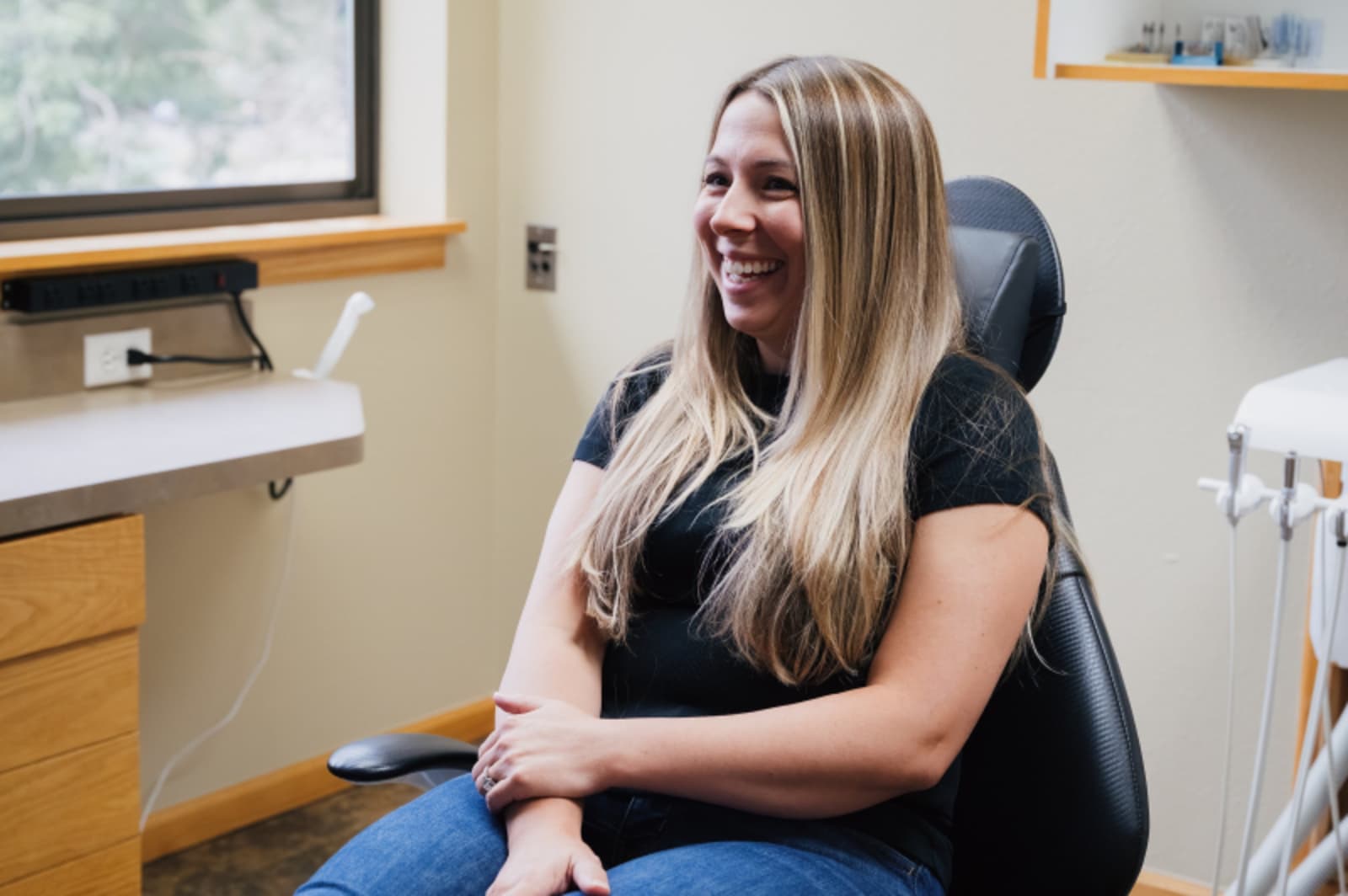 Female patient smiling in dental chair during treatment consultation