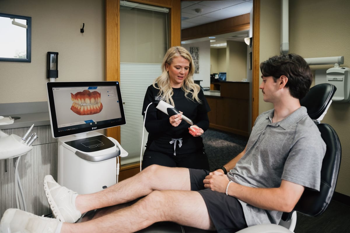 Dentist showing dental implant model to patient in treatment room at SoBo Dental Care.