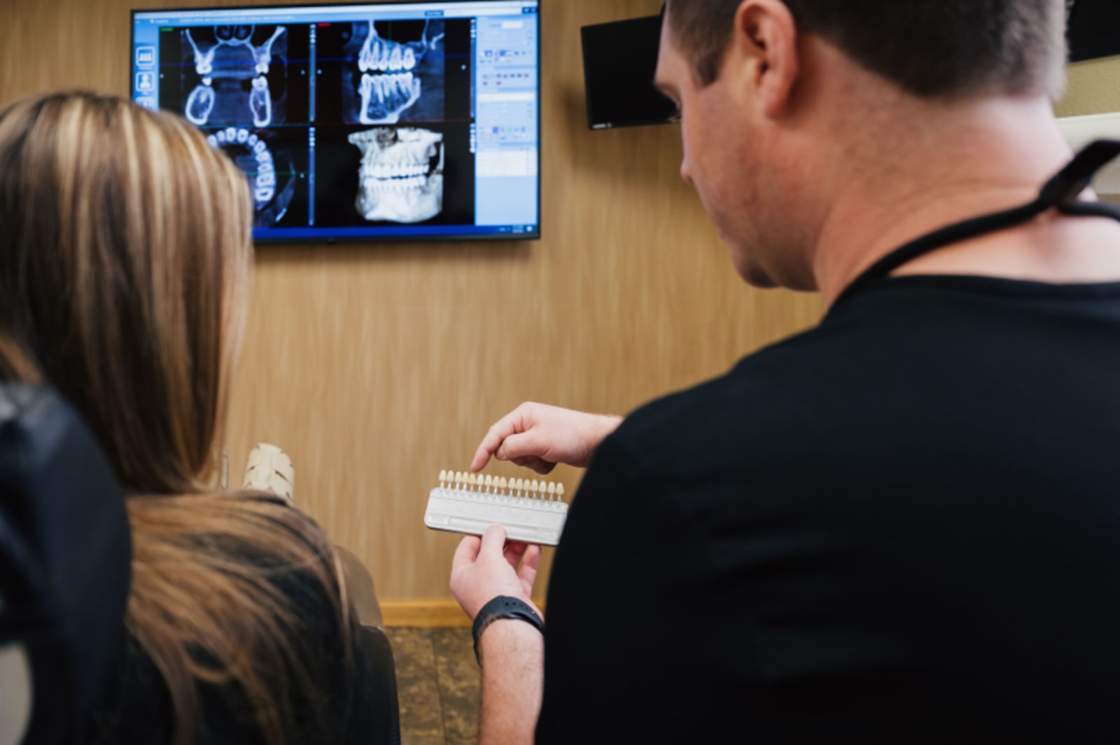 Dental professionals reviewing X-ray images on computer monitor with patient