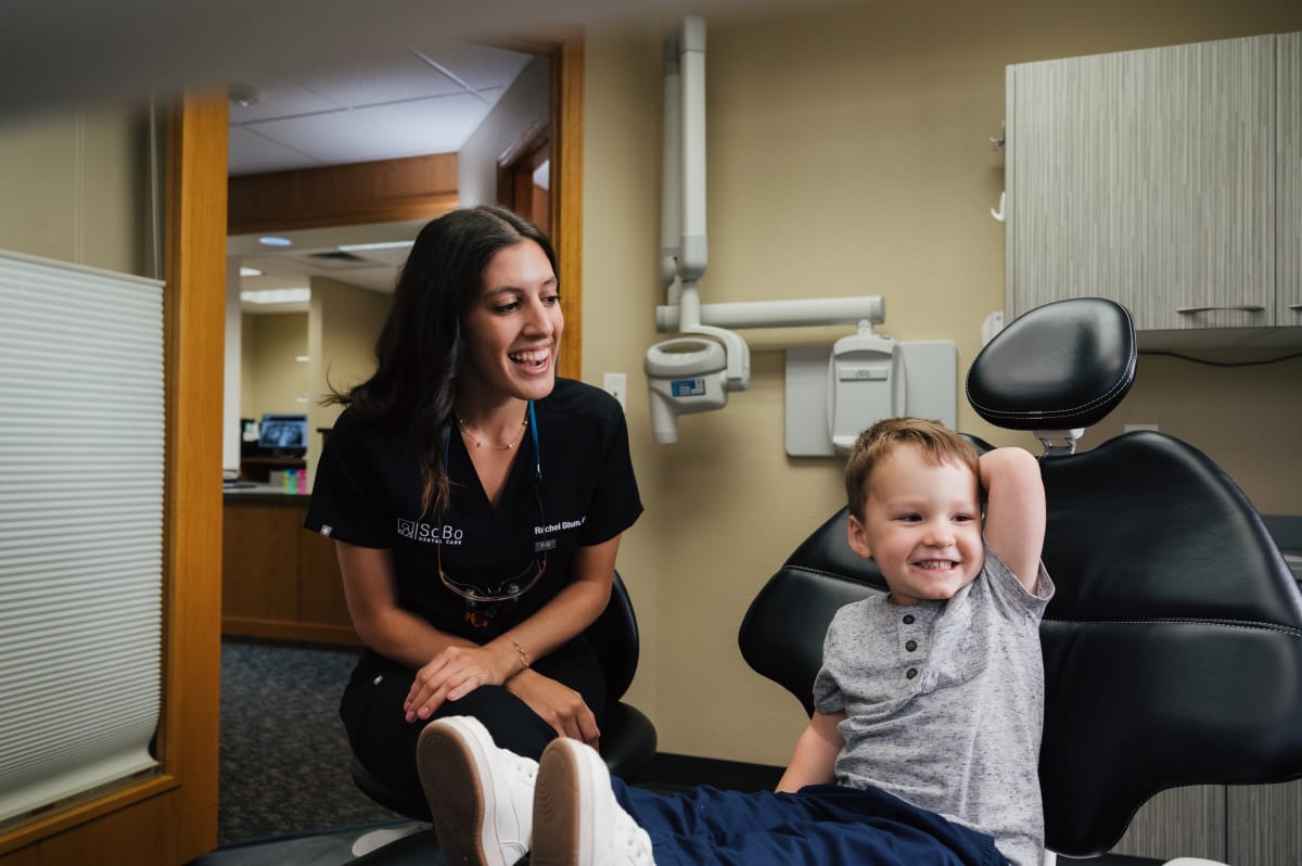 Pediatric dentist speaking with young child patient in dental treatment room at SoBo Dental Care.
