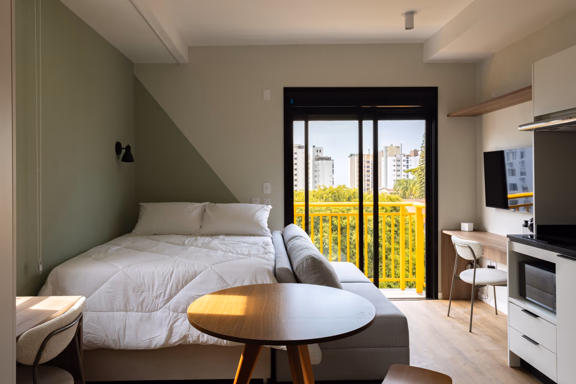 Apartamento mobiliado no Parkside Downtown, localizado no centro de Florianópolis, com ar-condicionado, geladeira, espelho, banheiro, geladeira, armários, bancos e mesa de madeira, pia na cozinha, cama, sofá e outros itens essenciais.