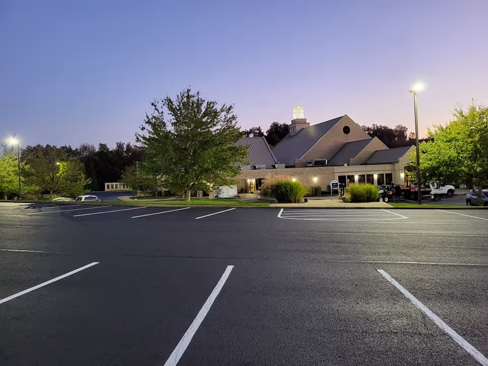 A newly paved and striped parking lot in front of a business at dusk.