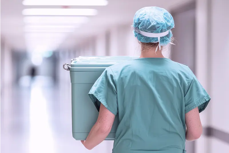Medical worker in uniform carrying a cooler box for organ transport