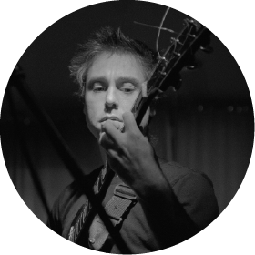 Black and white photo of a man playing an acoustic guitar.