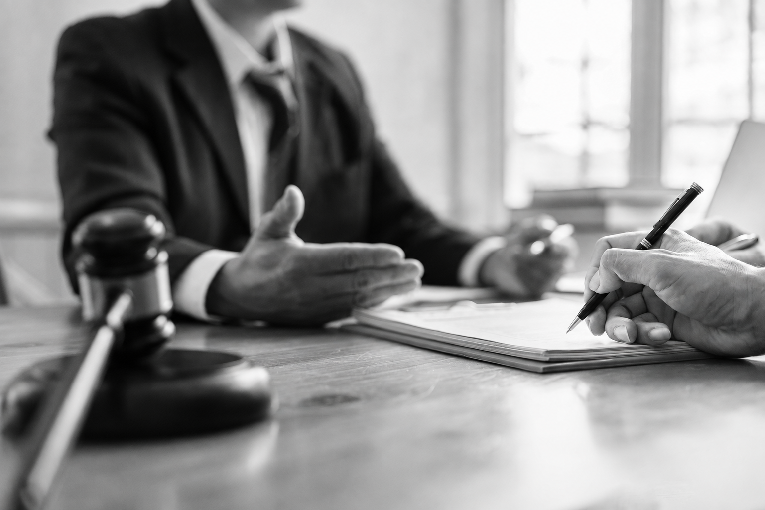A black-and-white photo of a personal injury victim talking to a lawyer as they take notes