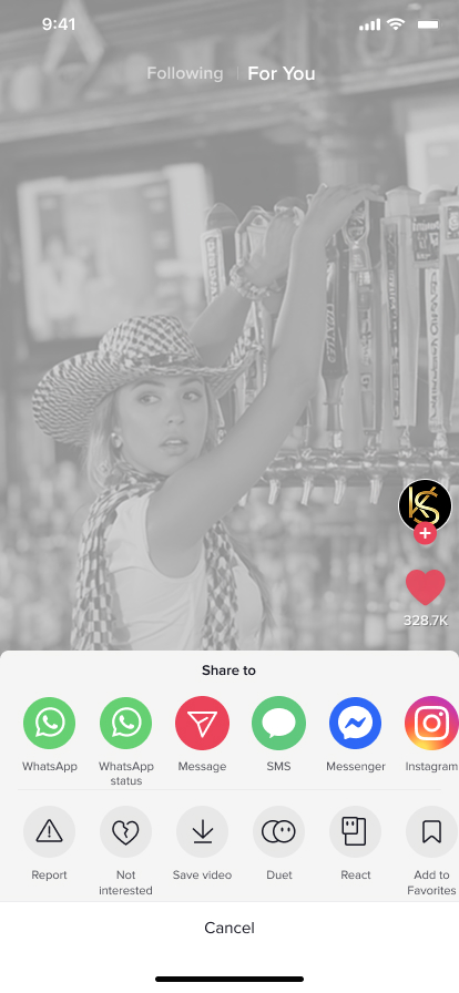 A bartender stands behind a busy, well-stocked bar in black and white.