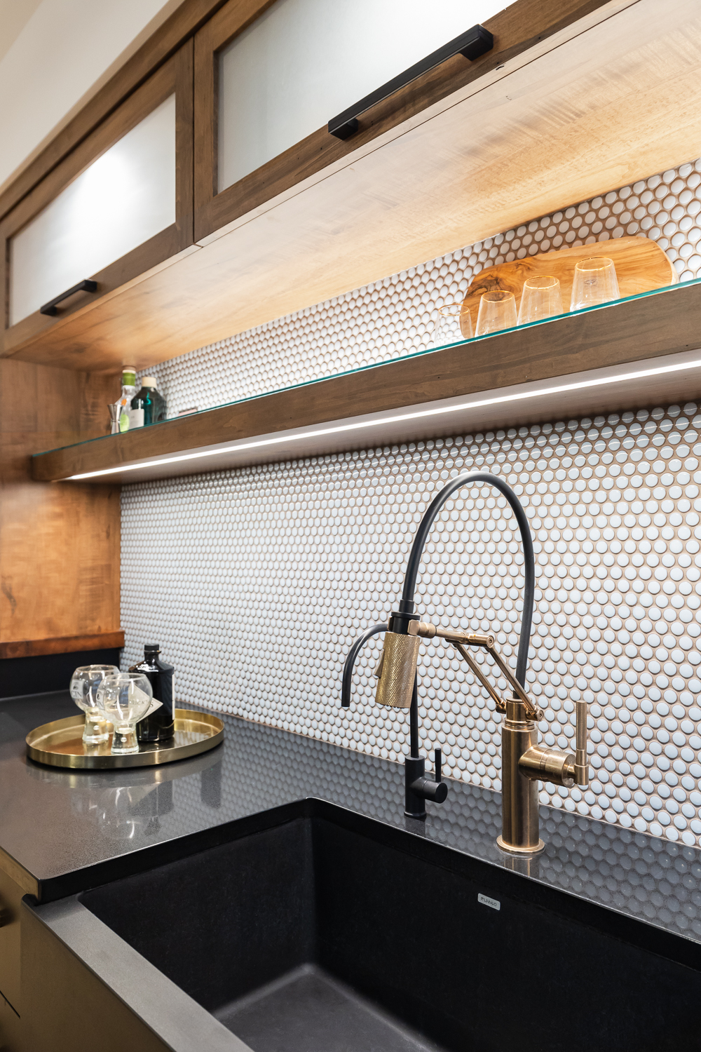 The subtle blue penny backsplash is just one part in the chorus of stunning elements in this bar that include gold and dramatic black accents.