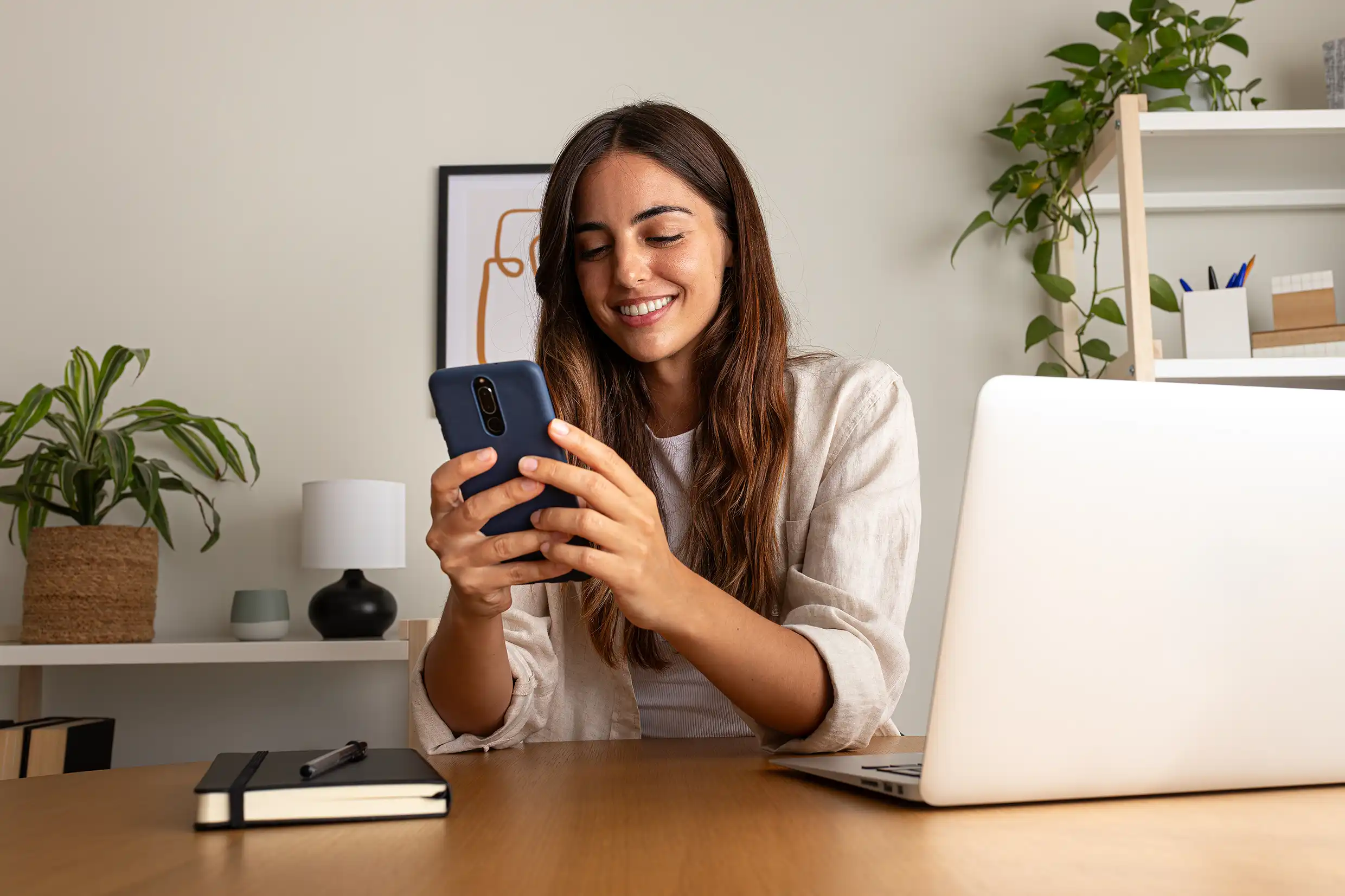 Young woman working using mobile phone working at home.