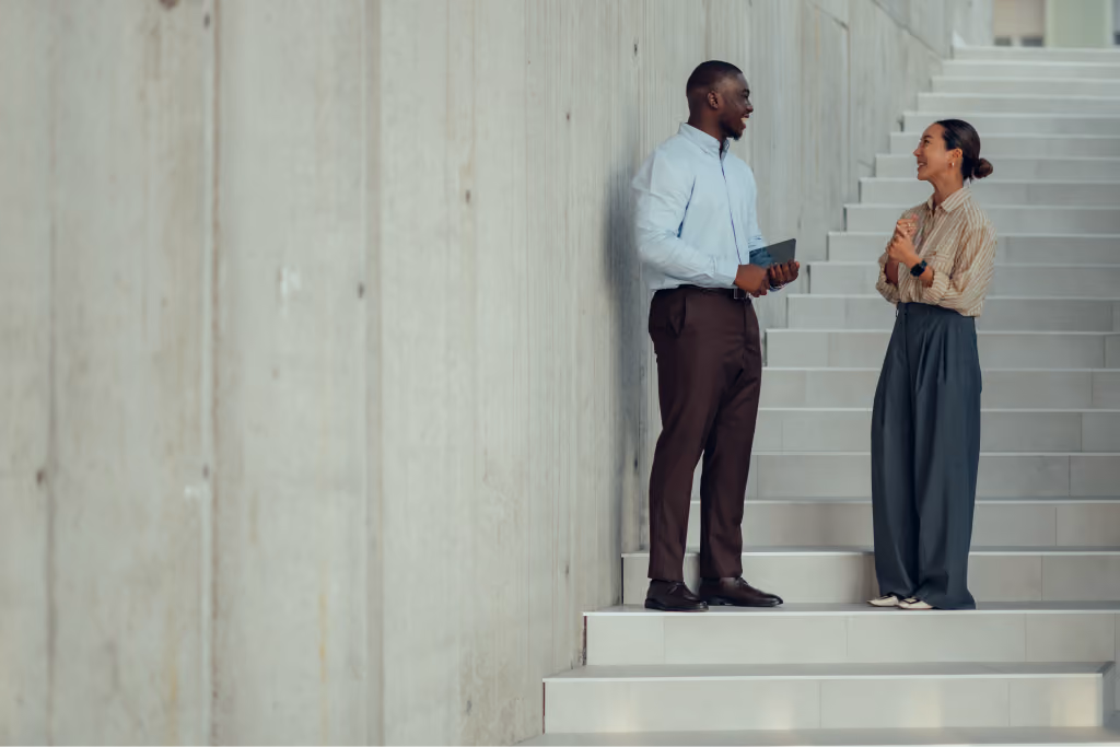 Two colleagues talking and smiling next to a staircase