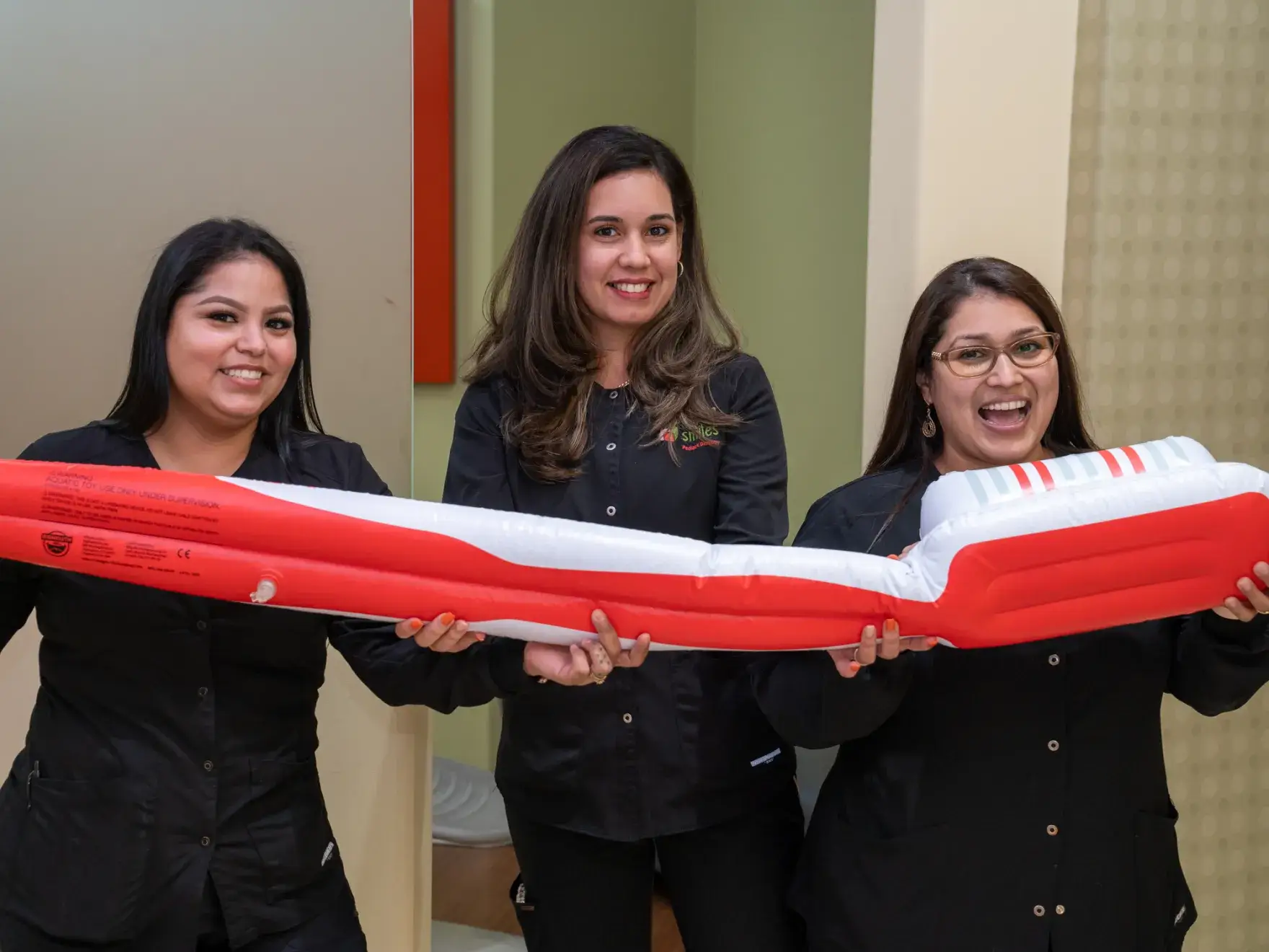 three women holding a large inflatable boat in a room