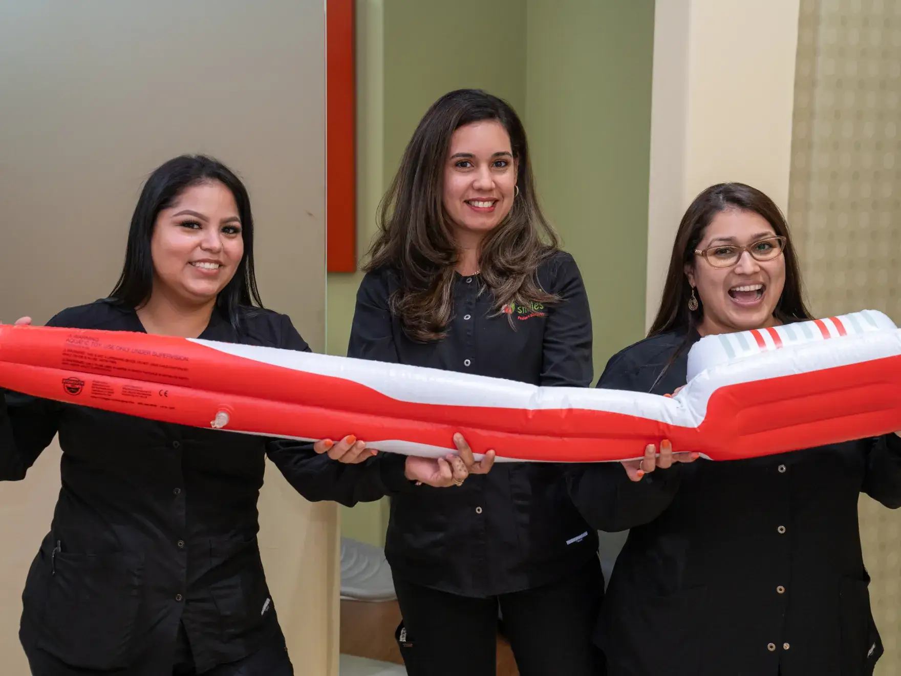 three women holding a large inflatable boat in a room