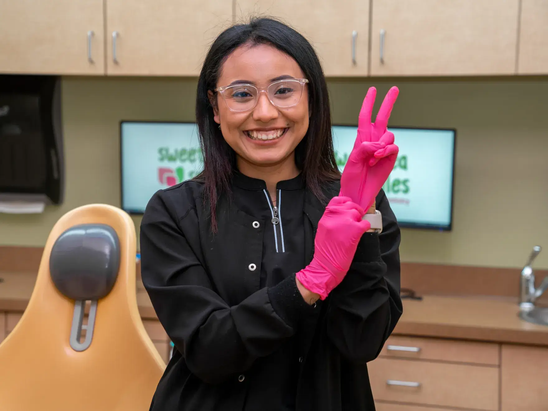 a woman wearing pink gloves holding up a peace sign