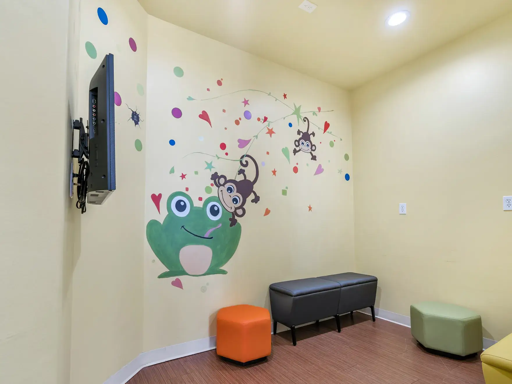 a child's room with a wall mural of a frog and a monkey