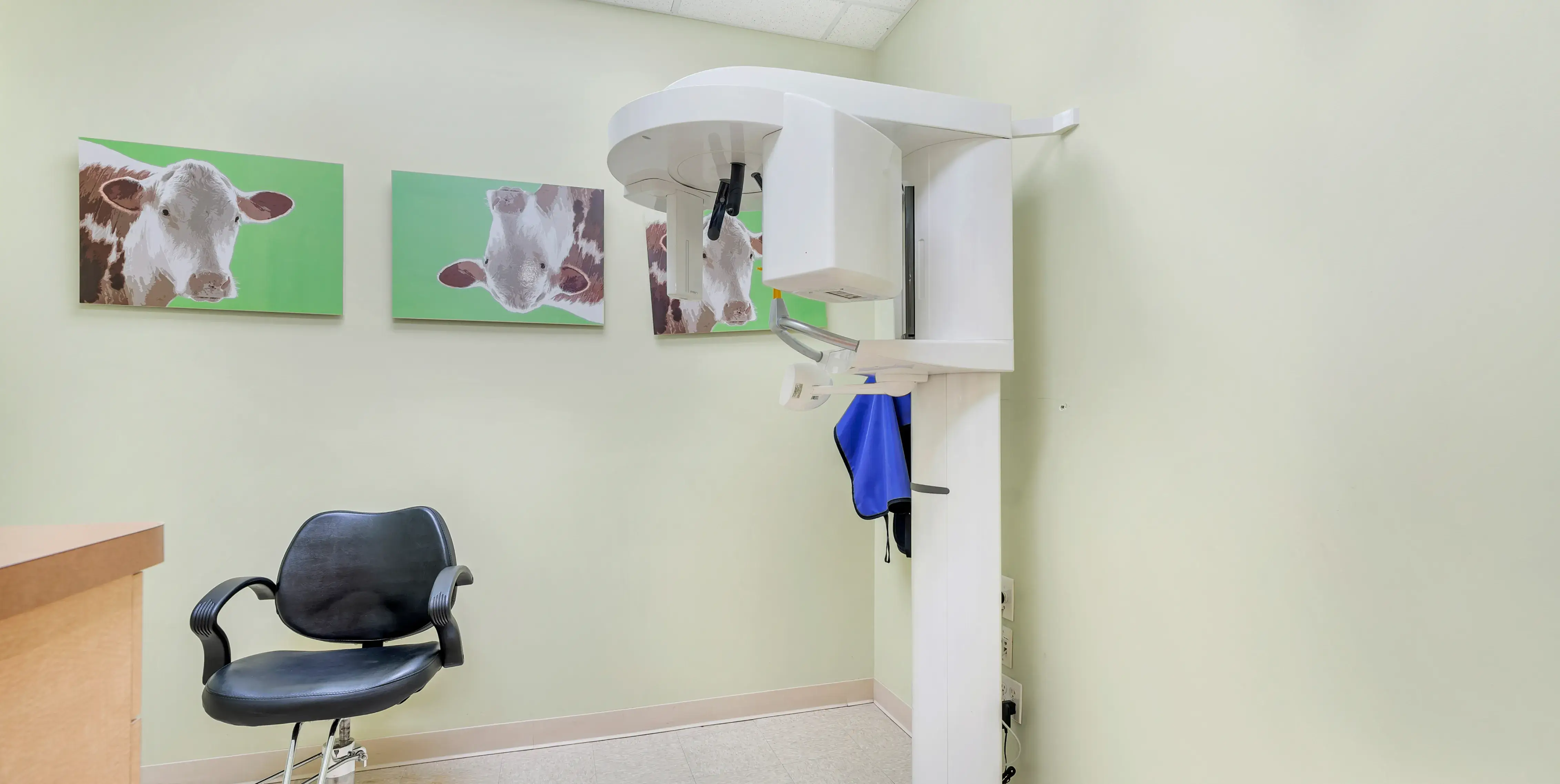 a dental office with a chair and paintings on the wall
