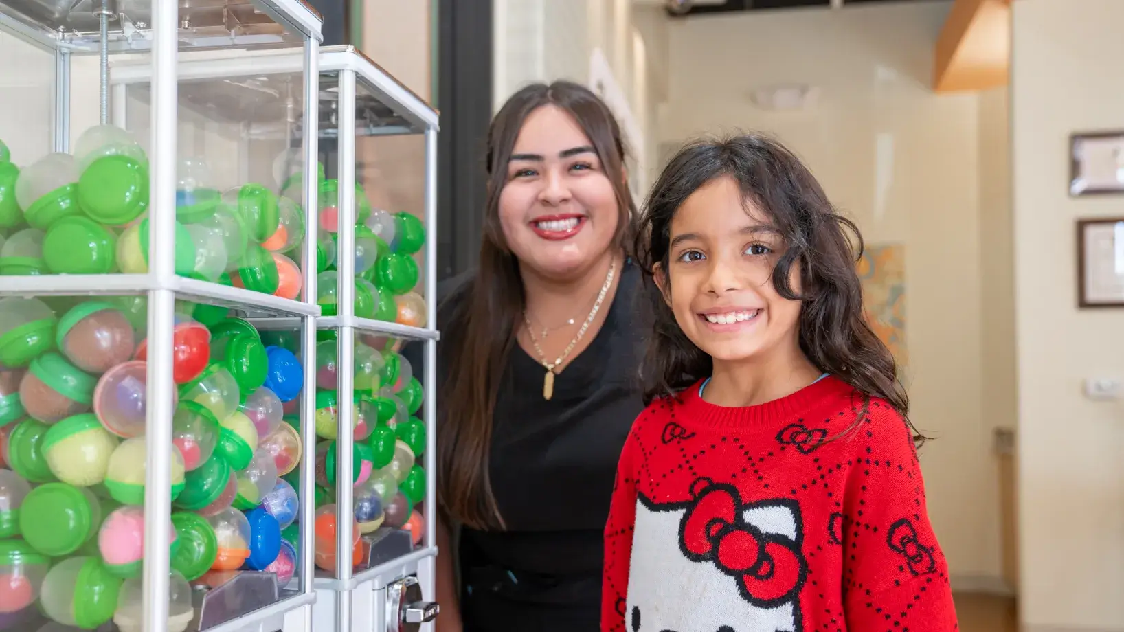a woman standing next to a little girl in front of a display of balloons