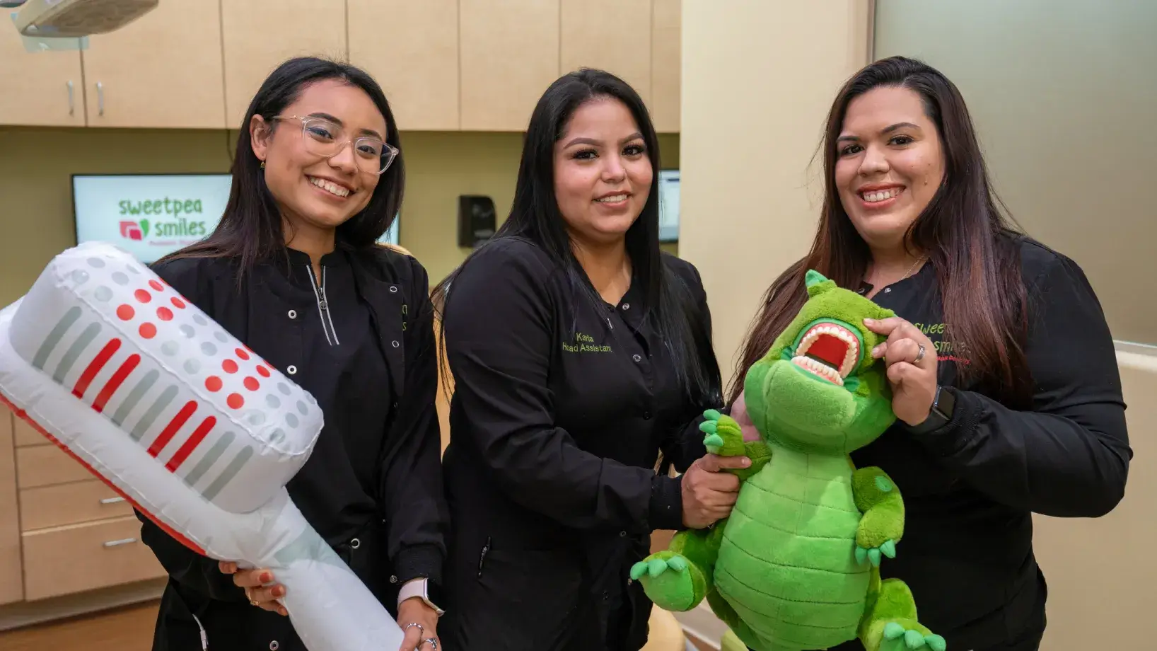 three women are holding a stuffed alligator and a toothbrush
