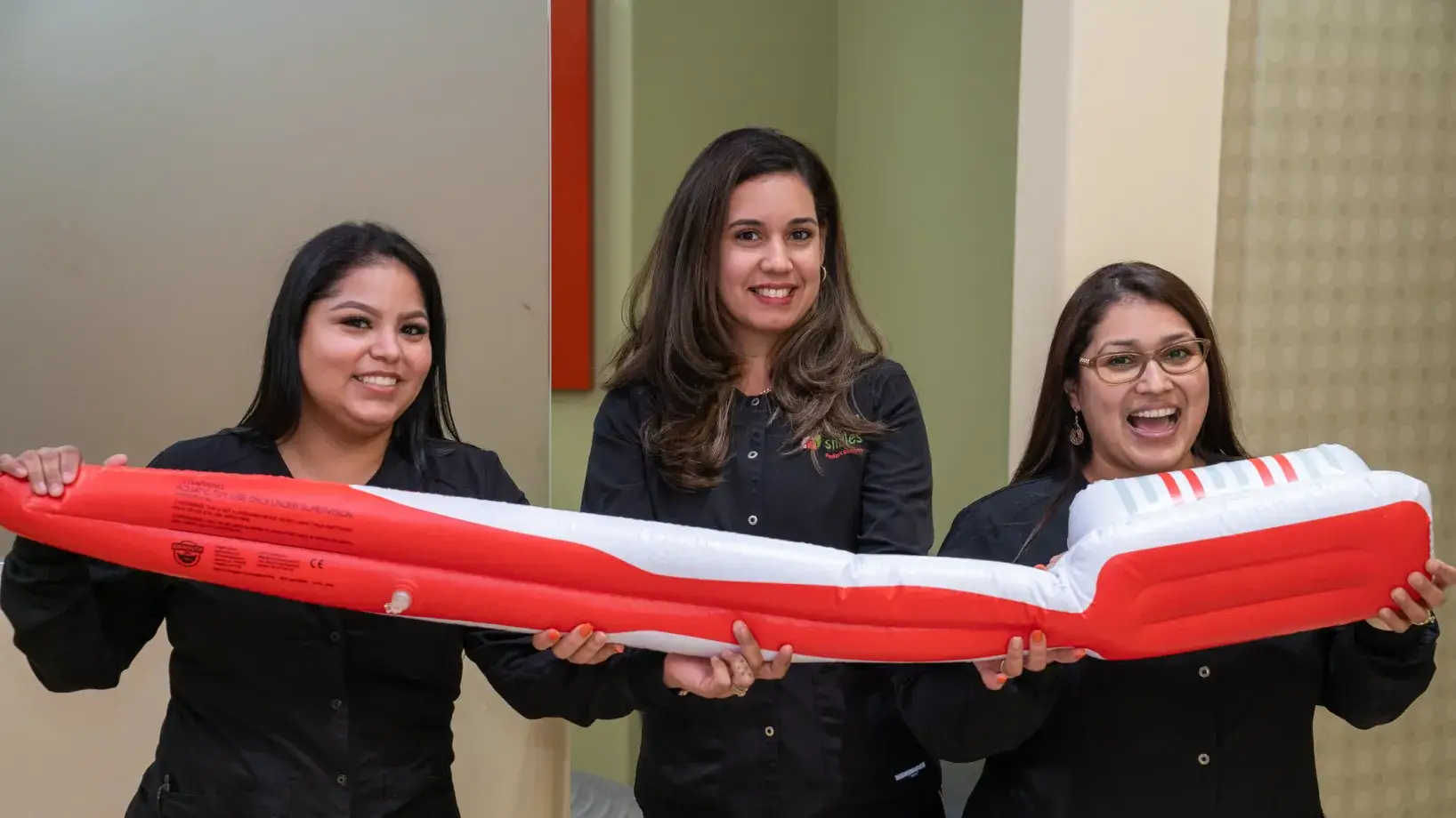 three women holding a large red and white object