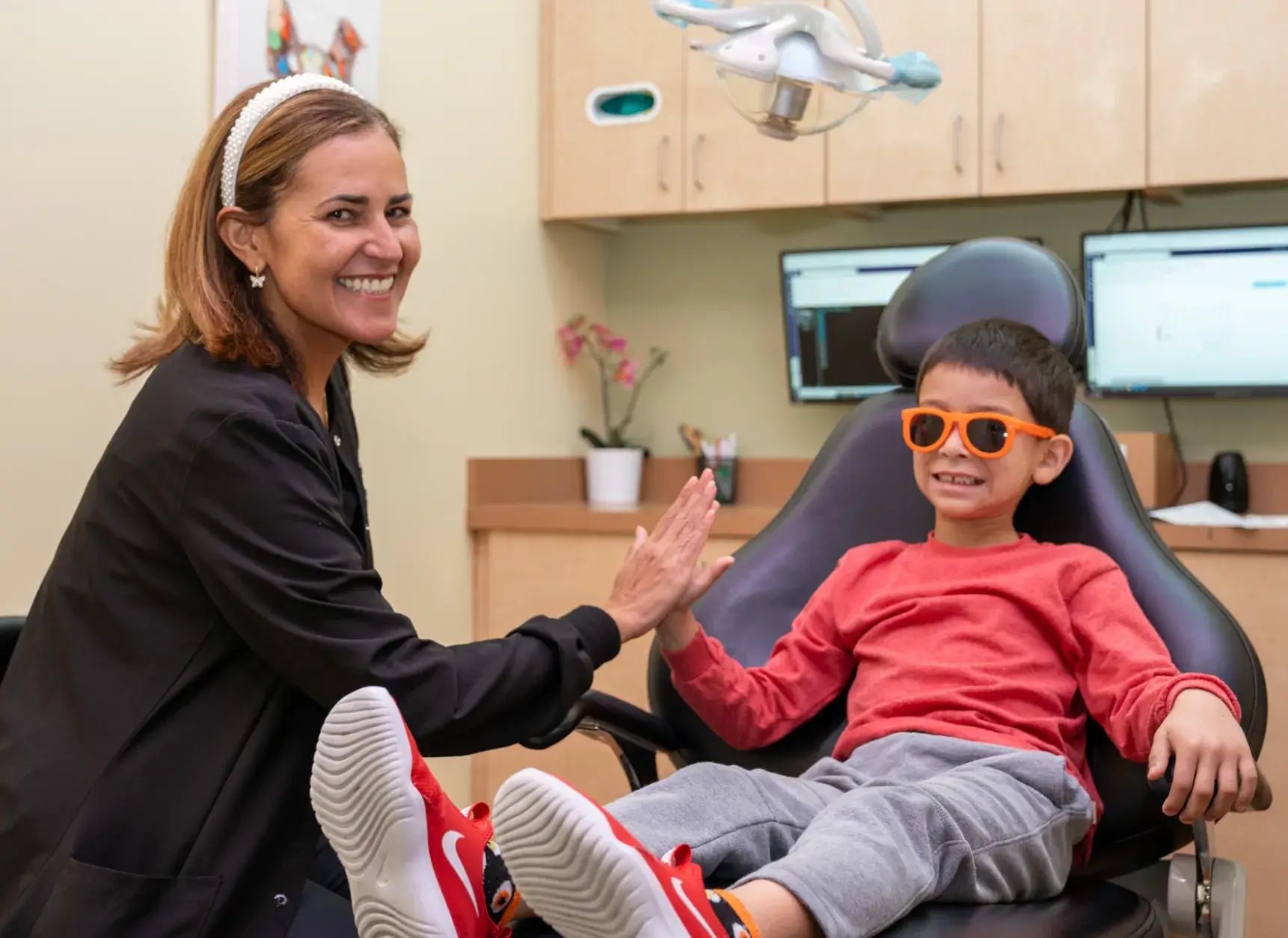 a woman smiles as a young boy sits in a dentist's chair