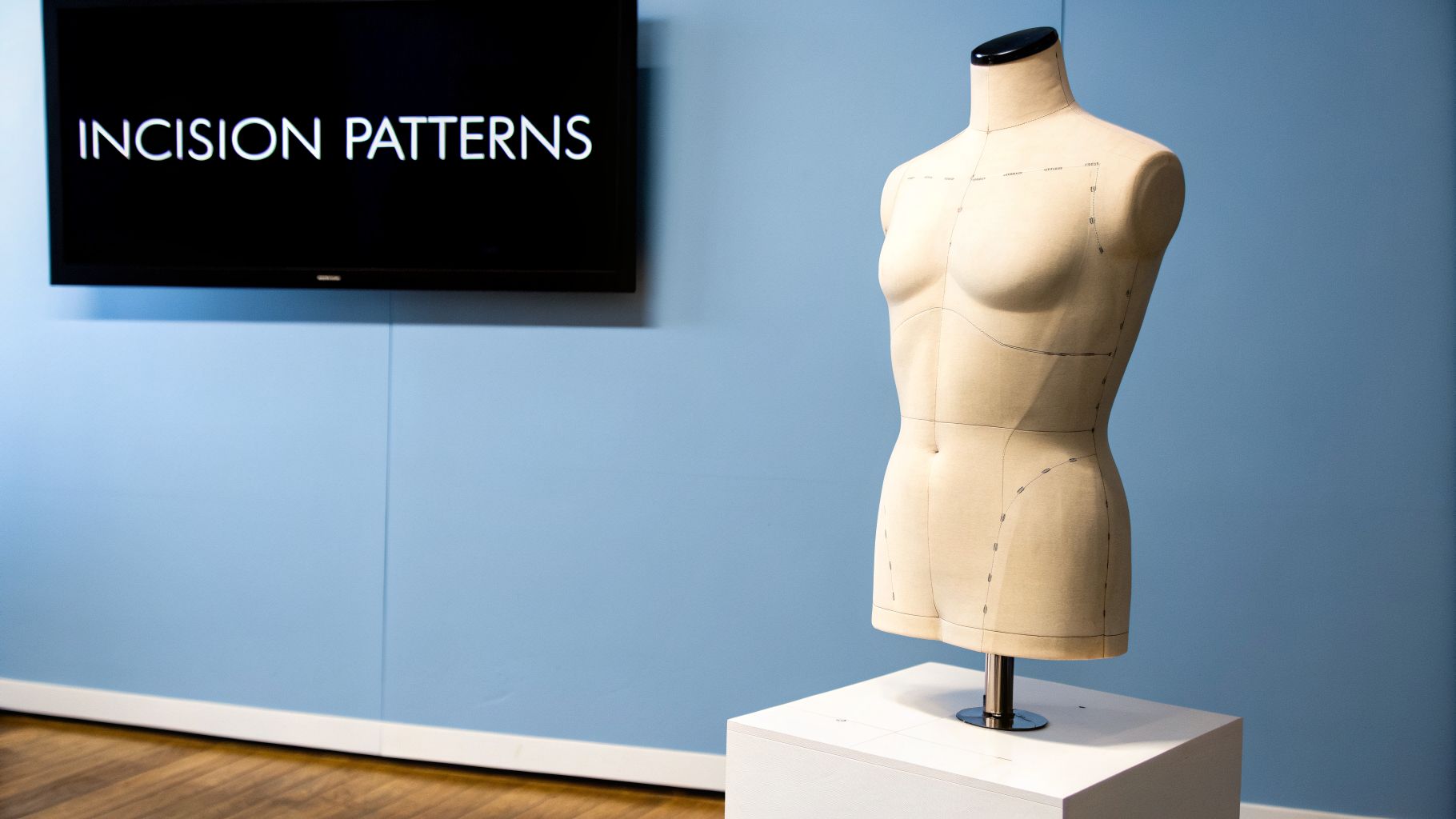 A beige dress form with pattern lines stands next to a screen displaying 'INCISION PATTERNS'.