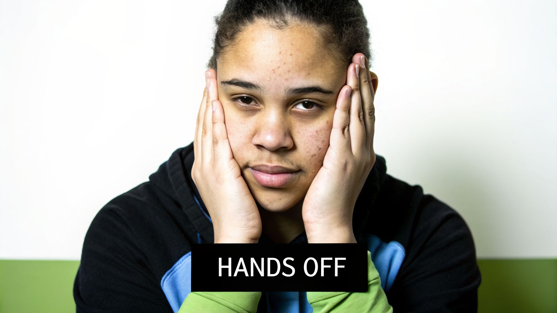 A young person with hands on their face, displaying a serious expression, with the overlaid text 'HANDS OFF'.