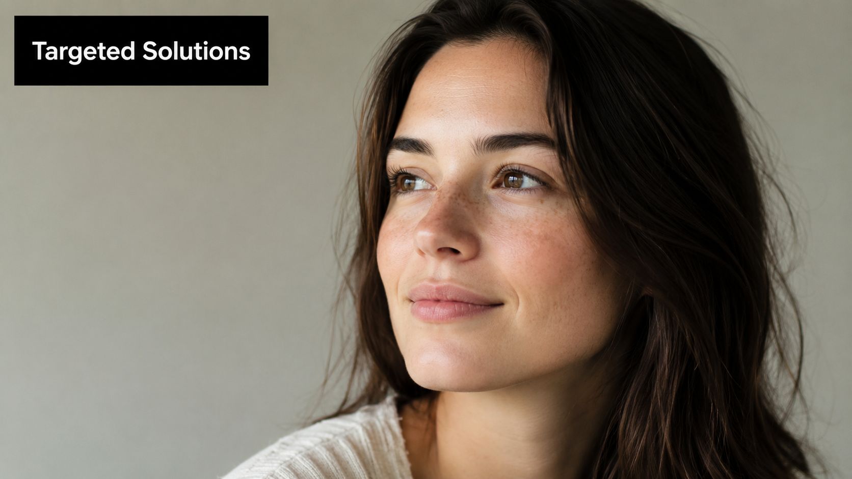 A close-up portrait of a smiling woman with natural skin texture looking towards the side.