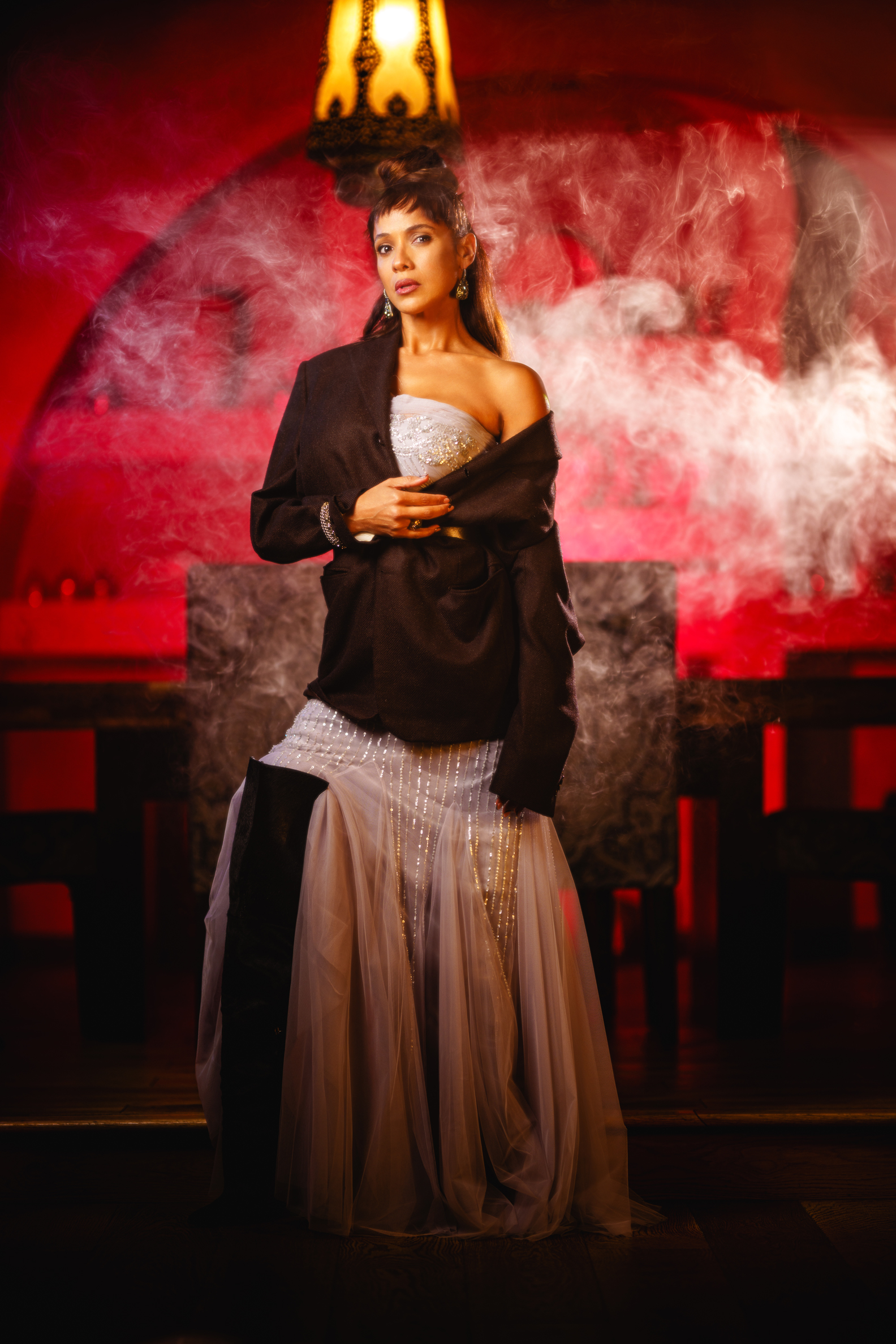 Dania Ramirez in dramatic red-lit room wearing evening gown during Empyreal Magazine photoshoot