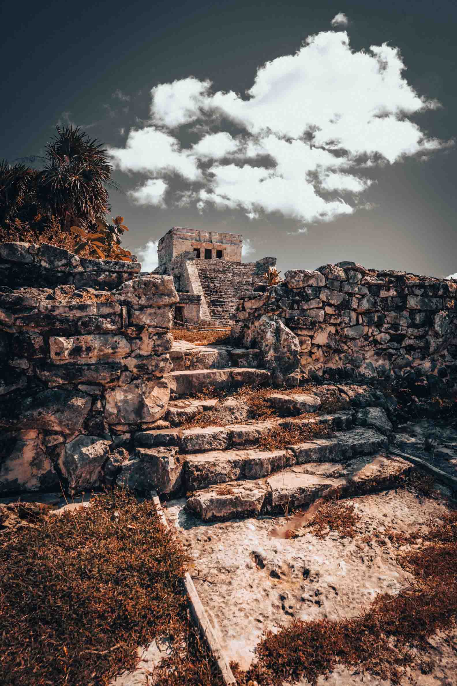 El Castillo temple at the ancient Maya archaeological site of Tulum, Mexico, photographed beneath a dramatic cloudy sky.