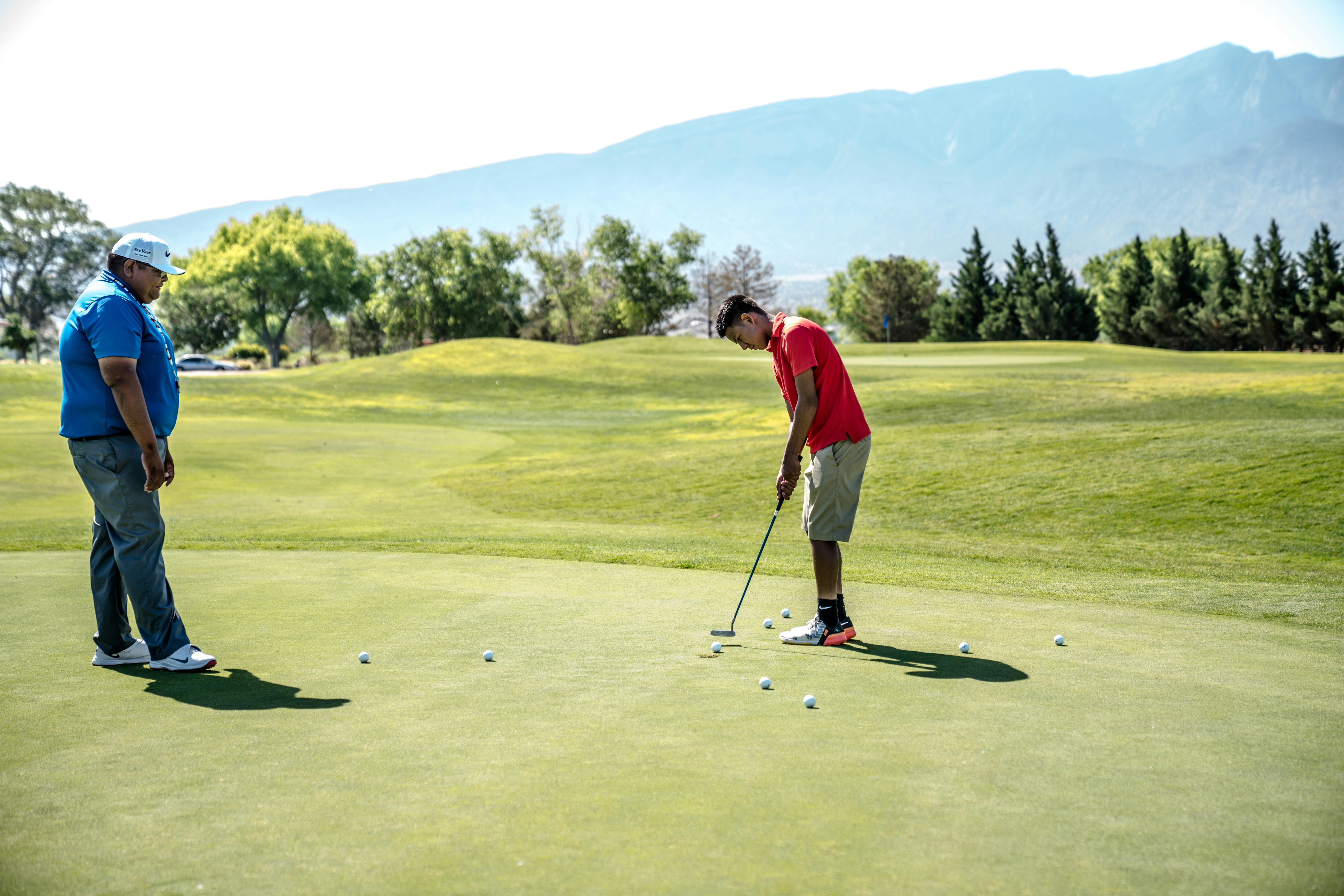 Two men playing golf and practicing putting on the green by Jopwell