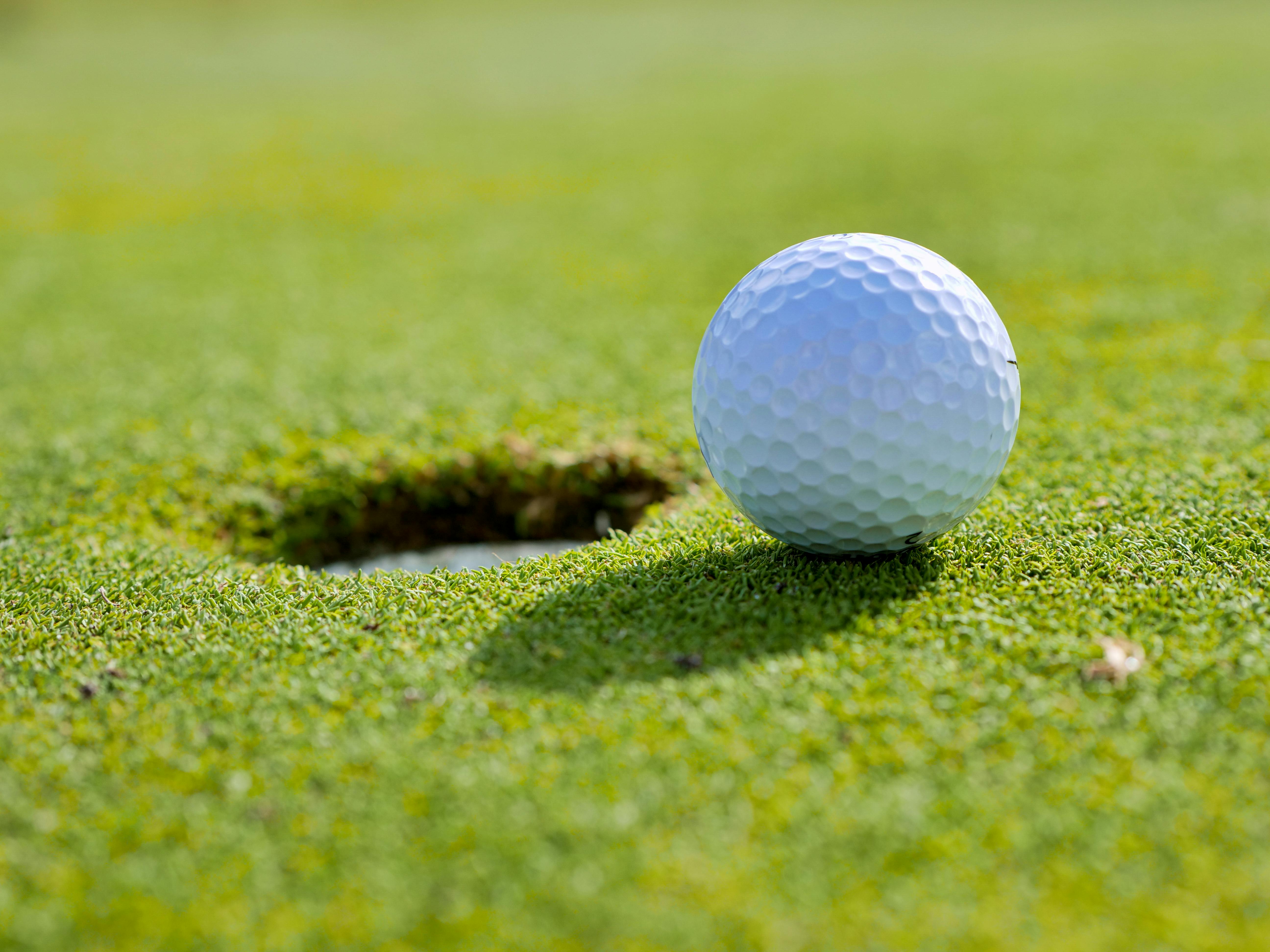 Close up photo of golf ball near a hole by Kindel Media