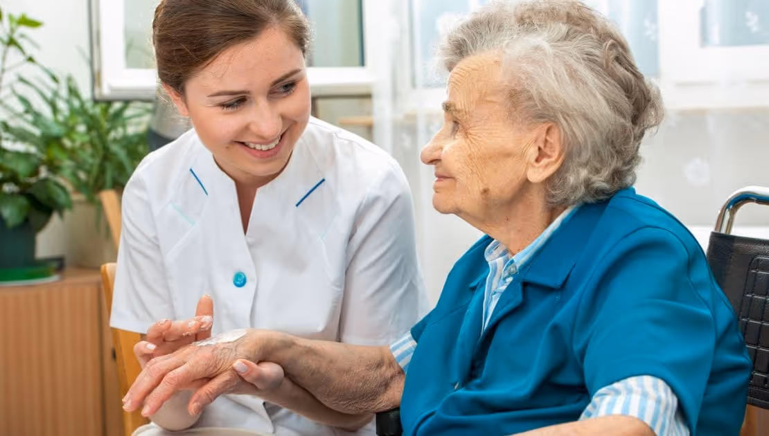 A carer is applying lotion on the hand of a dementia patient