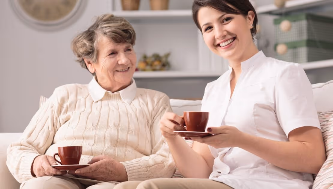A carer and her dementia patient are both having their coffee