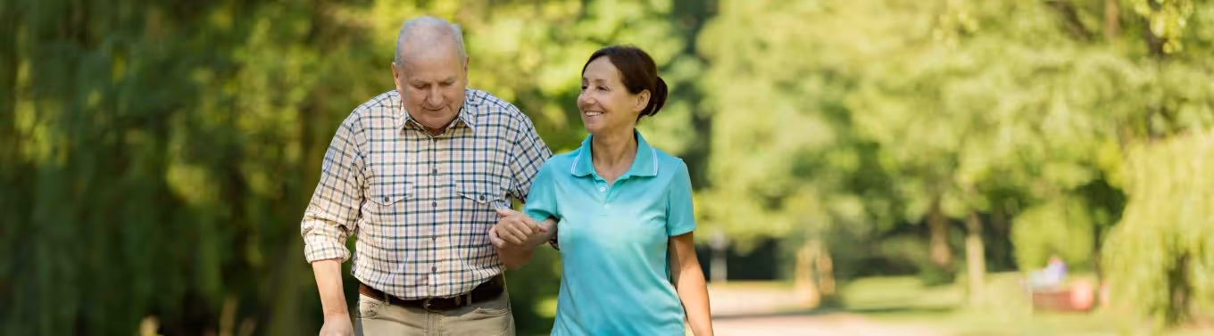 A daughter is helping her father to walk outdoors