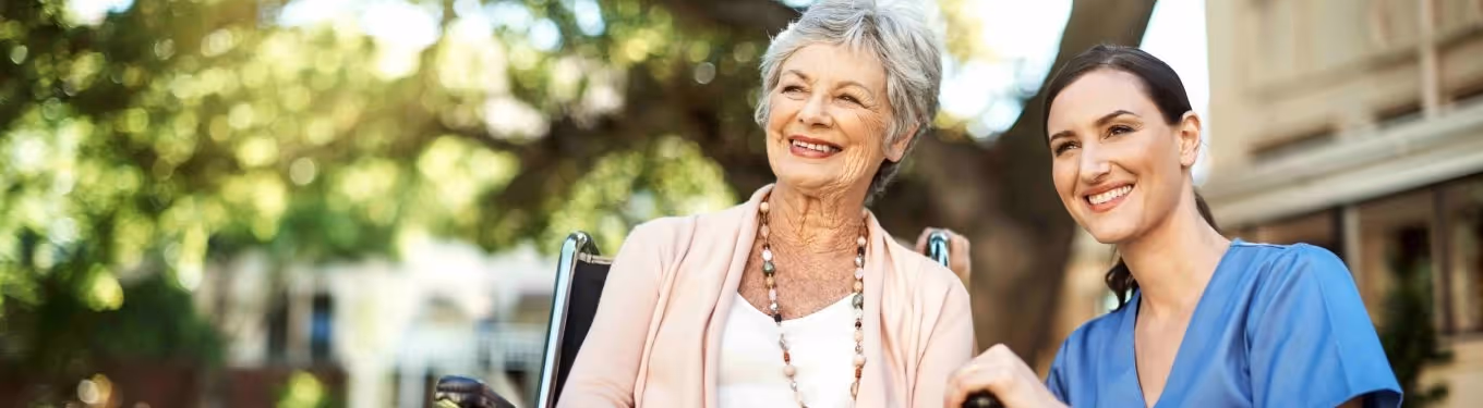A dementia patient and carer, both smiling, looking at something from a distance