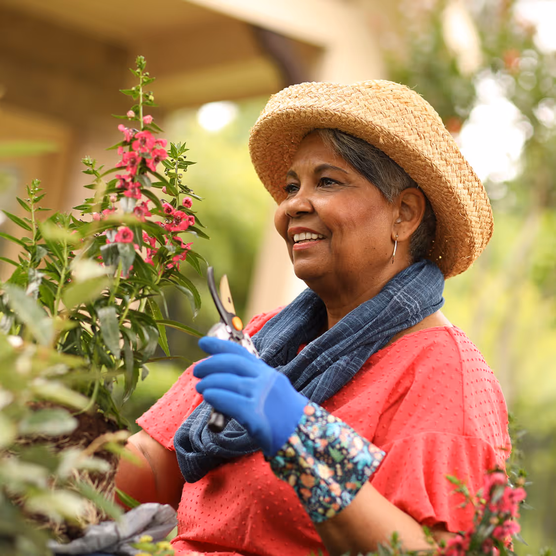 A woman trimming a flower plant outdoors