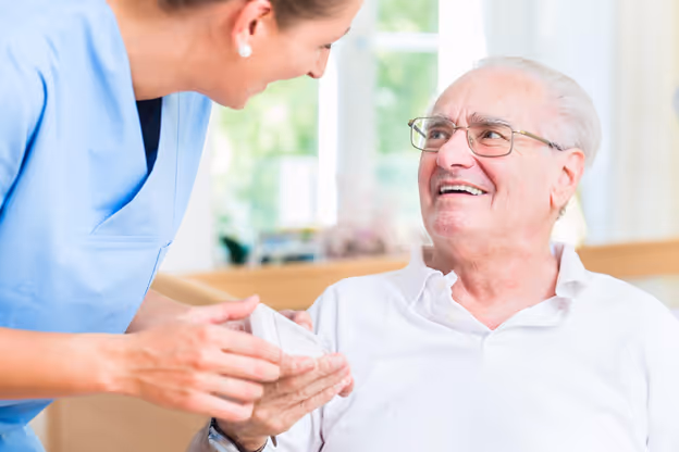 A senior patient with dementia is gladly receiving a remote control from a carer