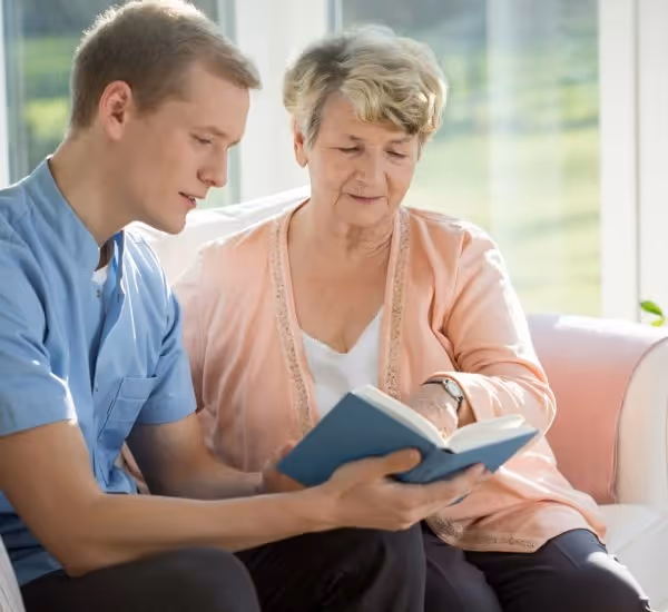A male carer reading a book with a dementia patient