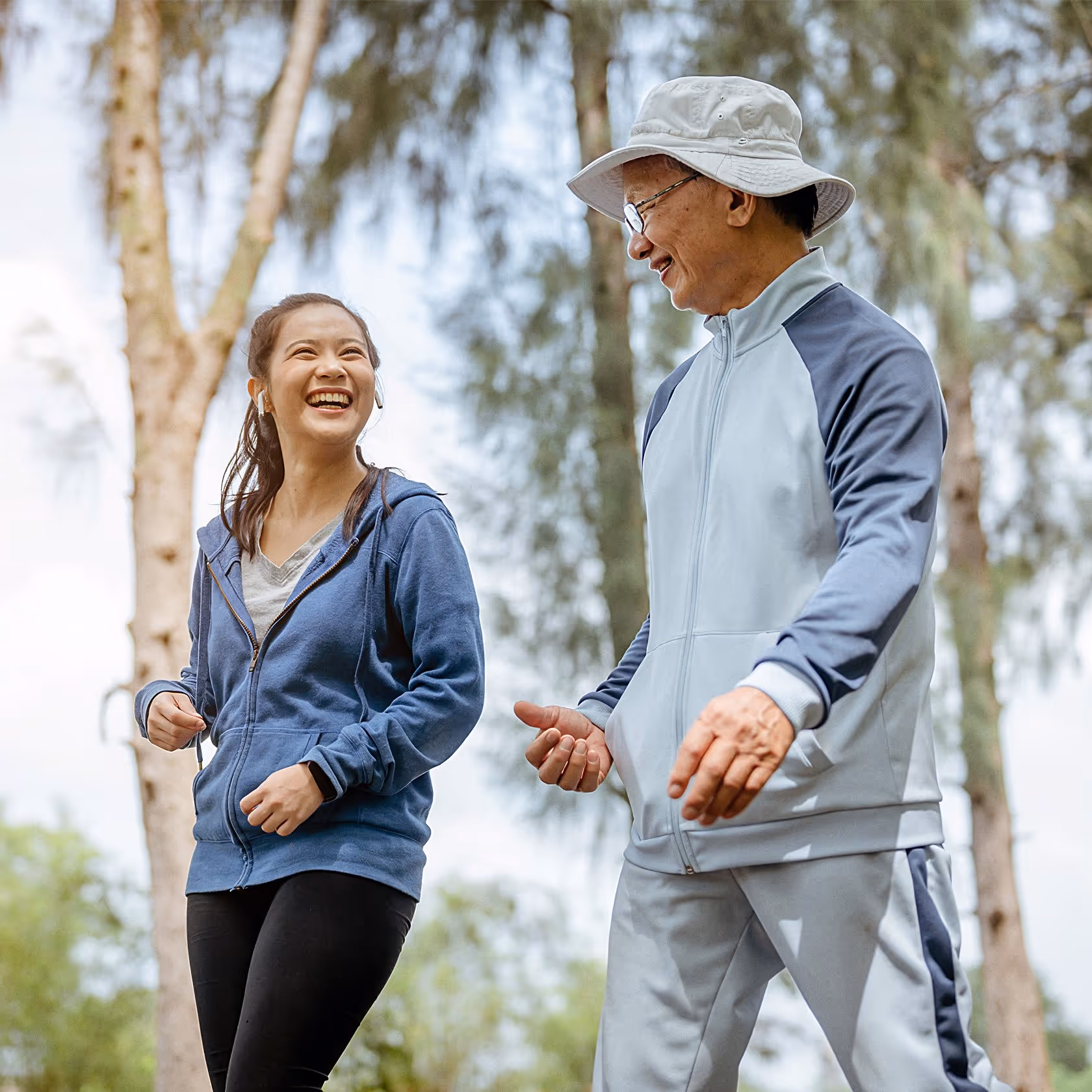 A daughter and father in workout clothes are having fun walking together outdoors