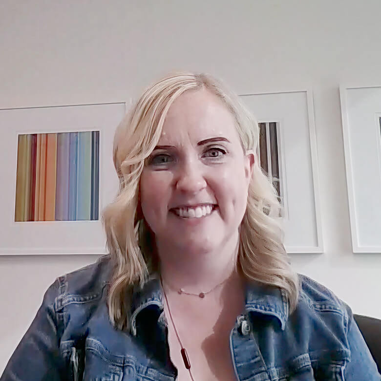 Client wearing a denim jacket giving a testimonial for Always Beyond IT services with colorful abstract art in the backgro...