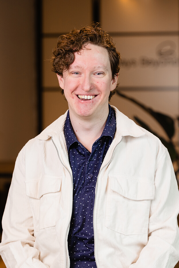 Team member at Always Beyond Calgary IT services wearing a white jacket over a navy patterned shirt.